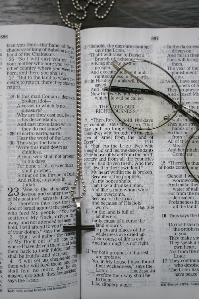digital An open Bible with a cross necklace and glasses placed on the pages, symbolizing faith.