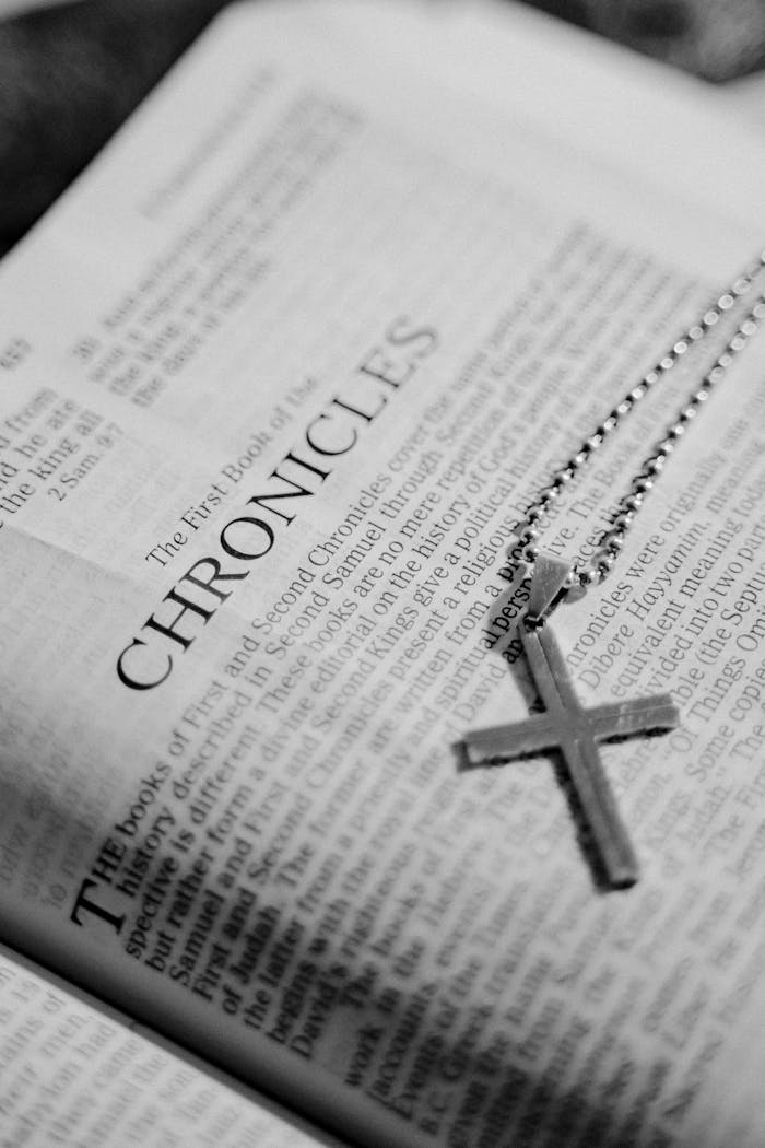 creative Black and white photo of a Bible page with a cross pendant on top, symbolizing faith.