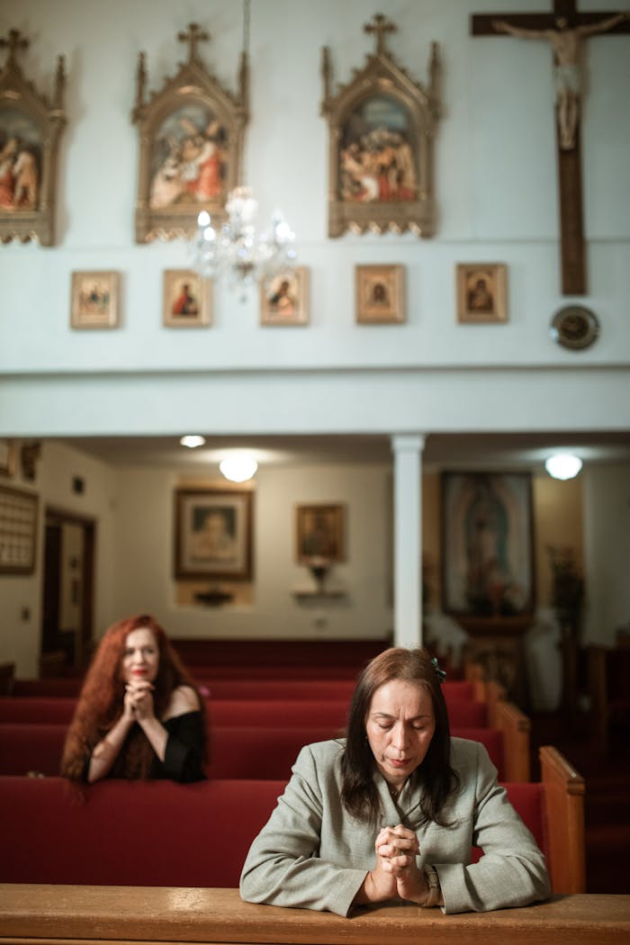 creative-01 Two women praying in a tranquil church, reflecting faith and spirituality.