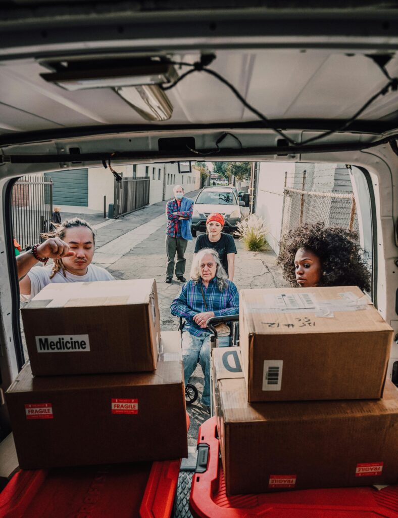 pexels photo 6646763 6646763 A diverse group of volunteers loading boxes labeled 'Medicine' into a van for community aid.