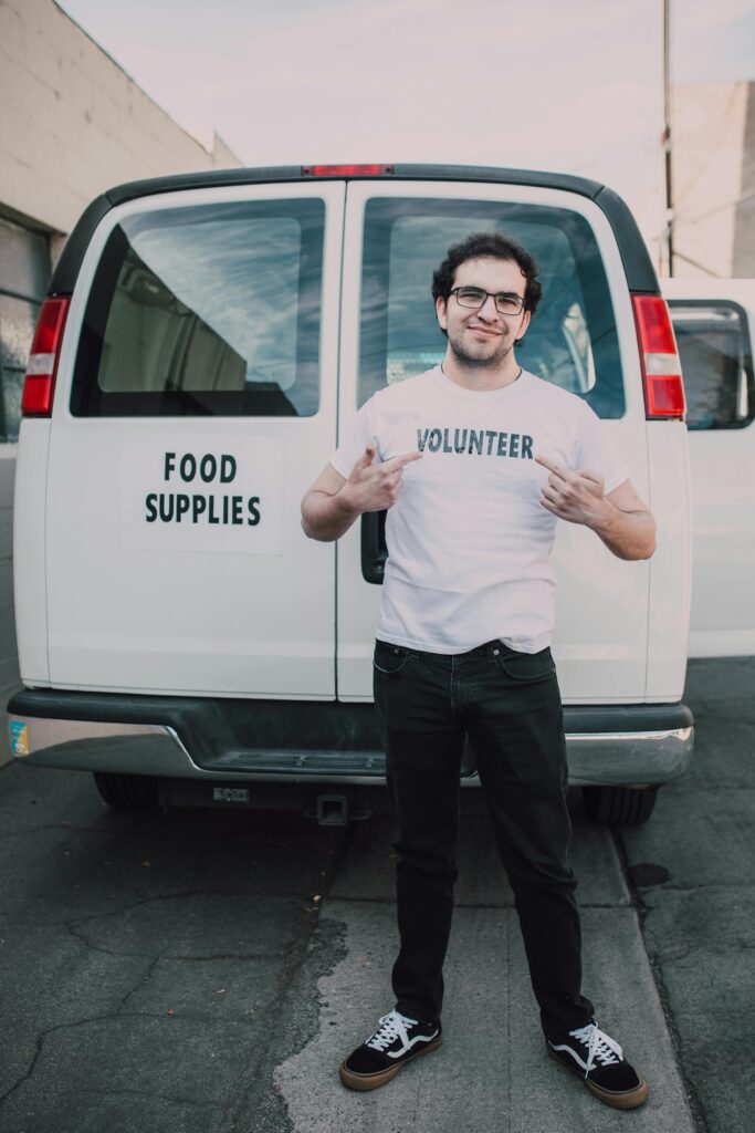 Man standing in front of a food supplies van, promoting volunteerism.