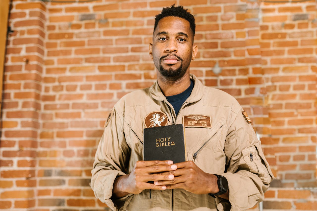 Services-01 A military veteran holding the Holy Bible in front of a brick wall background.